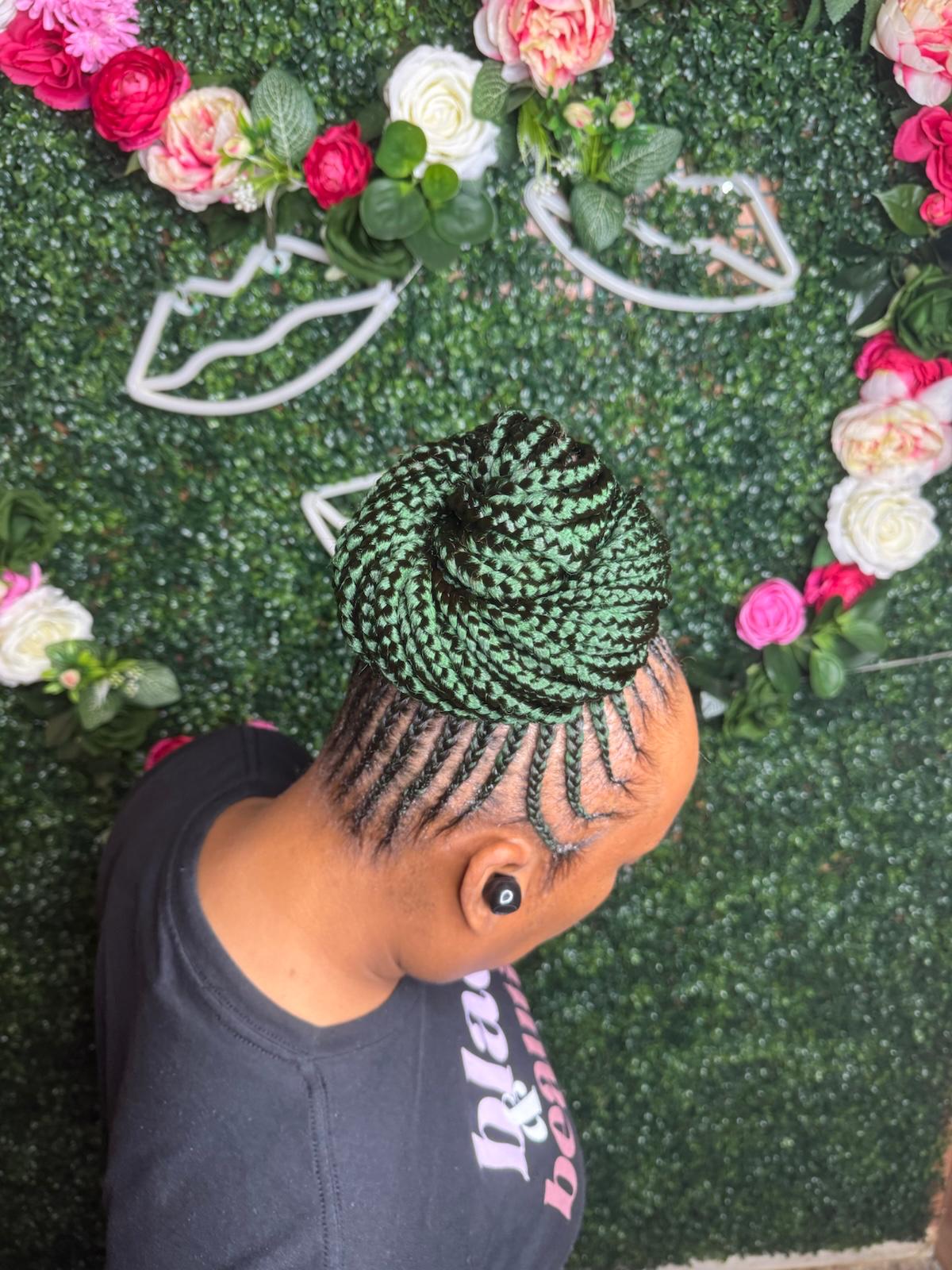 Cornrow updo with green braided bun at Braids by estal